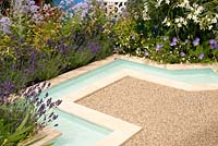 Angular still turquoise water rill with flower bed planted with Lavandula Hidcote, Nerium oleander Album and Geranium sanguineum Max Frei in the Noble Caledonia: Spirit of the Aegean garden RHS Hampton Court Palace Flower Show 2015 