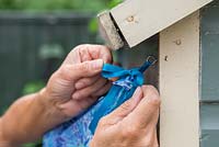 Securing the ends of the fabric to the screw eyes - affixing awning to shed