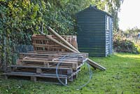 Materials required to construct an upcycled Three-Bin composting system. Wooden pallets, metal wire, strong wooden stakes, a saw and a post driver