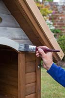 Painting a dog kennel with wood paint. Two layers will ensure protection against the elements