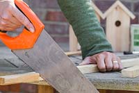 Use a ruler and measure the roof of the bird house, sawing off wooden batons to match the required lengths