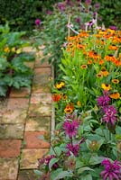 Reclaimed pamment garden path bordered by Monarda 'on parade', and Helenium 'Sahin's Early Flowerer'