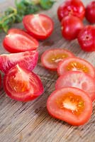 Whole, sliced and halved tomatoes - Lycopersicon esculentum 'Alicante' on wooden table