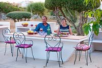 Jonathan and Jo Baillie sitting at outdoor, built-in table with barbeque. Alaior, Menorca. 