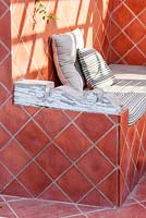 Outdoor terracotta tiled seating area with rustic wooden arm rest.  