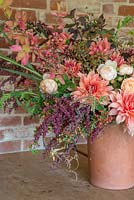 Vibrant bouquet in a large terracotta pot, made with Wood sage, Euonymus europaeus, Rosa 'Ambridge Rose', Dahlia 'Labyrinth', Rosebay willowherb seed pods, Hydrangea arborescens 'Annabelle', Atriplex hortensis 'Rubra', Rubus fruticosus, Cosmos bipinnatus 'Purity', Panicum elegans 'Frosted Explosion', Crataegus monogyna, Dahlia 'Babylon Bronze', Helianthus annuus 'Ruby Eclipse', Zinnia elegans 'Queen Red Lime', Panicum violaceum, Amaranth, Lupin and Eschscholzia californica 'Peach Sorbet'