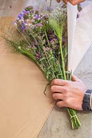 Creating flower bunches for a farmers market. Wrapping a bundle of Origanum laevigatum 'Herrenhausen', Panicum elegans 'Frosted Explosion' and Centaurea in brown paper