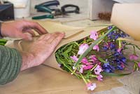 Creating flower bunches for a farmers market. Wrapping a bundle of Cleome hassleriana 'Rose Queen', Agapanthus and Nicotiana in brown paper