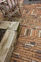 Patio made from red bricks with a wood block planter