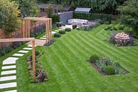 Wide overview of the garden featuring the path, pergola, gabion feature and sunken seating area