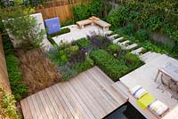 View onto formal town garden in London with decking, box cubes, Agapanthus 'Enigma', Salvia 'Mainacht', 'Purpurescens' and 'Caradonna', Carex buchananii. Designer: Charlotte Rowe