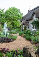 Cottage garden with gravel path and blue painted obelisk