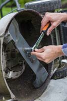 Reattaching the reconditioned and sharpened lawn mower blade with a socket and spanner set