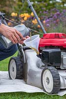 Whilst the lawn mower is upright, use a funnel to fill the lawn mower with new engine oil