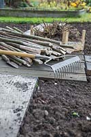 Materials required for developing a cutting garden. Hazel stick plant labels, string, rake, tubers, bulbs and seeds.