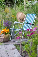 A deckchair with a selection of cut flowers. Calendula officinalis, Verbena bonariensis, Allium seedheads and Foeniculum vulgare