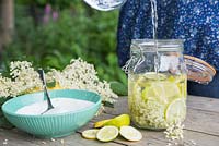 Making an Elderflower drink. Adding water to the mix of sliced Lemon, Lime, Sugar and Elderberry flowers