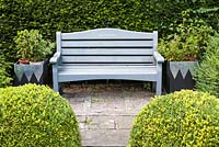 Grey-painted Carpe Diem seat with metal planters. The Ridler Garden, Swansea, South Wales. July. Designed and created by Tony Ridler