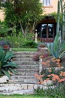 Vista up from the lake-bed garden to the door of the house lined with exotic planting. La Case Biviere, Sicily 