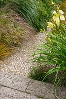 Gravel path with Hemerocallis and ornamental grasses.
