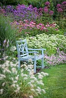 Blue Bench infront of mixed border. Summer. 