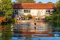 Family relaxing by and swimming in a swimming pond