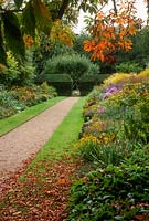 View of herbaceous borders in  late September. Gravel path and grass strips.