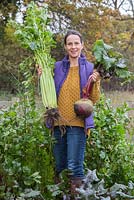 Woman holding overgrown produce of beetroot and celery