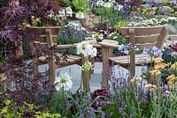 Profusely planted seating area with a view of the waterfall in 'The Water Garden' at RHS Tatton Flower Show 2015