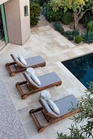 View of modern swimming pool with outside seating area and sun loungers.