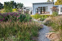 Prairie planting in small town garden. Geranium 'Ann Thompson', Stipa tenuissima, Calamagrostis brachytricha, Molinia caerulea 'Dauerstrahl', Aster 'Septemberrubin',  Panicum virgatum 'Shenandoah', Miscanthus sinensis 'Malepartus'. Van de Voorde garden Design: Tom de Witte