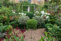 In 12m x 6m town garden, formal parterre with box and variegated holly standards, and box edged beds of Phlox paniculata 'David', Aconitum 'Spark's Variety', salvia, sanguisorba, crocosmia and red or pink persicarias.