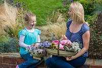 Mother and daughter with their Sussex trugs, handcrafted by Charlie Groves, filled with cut flowers.
