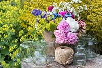 Making a summer posie for freshly cut flowers in glass jars covered with twine.