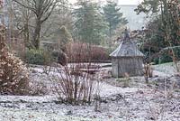 Wooden summerhouse in a dormant bog garden dusted with a light icing of snow.