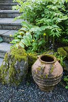 Terracotta pot at the base of steps leading down into the 'best' garden at the front of the house, the most formal area of the garden, with Solomon's Seal and self seeded Welsh poppies and forget-me-nots. Windy Hall, Windermere, Cumbria, UK