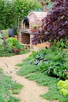 Path leading to outdoor oven, Acer palmatum 'Garnet' - 'A Fruity Story' - RHS Malvern Spring Festival 2014