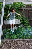 Archie, 7, on the swing in the play area of the garden.