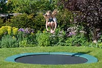 11-year-old Ava on the trampoline, set into the lawn.
