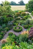 An overhead view of a south facing suburban garden designed around interlinking circles. Deep borders are mainly herbaceaous with shrubs and shaped box providing structure and framing the planting throughout the year.