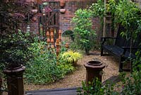 A small gravel garden with recycled terracotta pot sculpture providing a focal point.