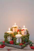 Advent candles with numbered clay plates, Pyracantha and Moss