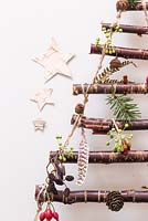 A hanging Christmas tree made with Birch branches. Decorations feature Pine cones, feathers, Rose hips and Ivy seed heads