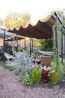 View into seating area showing Acapulco chairs and hammock under a retractable shade hut canopy. Kalanchoe hildebrantii 'Silver Spoons' in the foreground