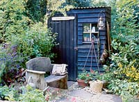 Wooden shed and rustic wooden bench with hurricane lamp and fishing weights. Cfs 01 Design Sarah Sanderson
