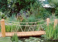 Wood and rope bridge over stream, marginal and aquatic planting, Credit Hampton Court 2001. Design Mark Davis, tranquility