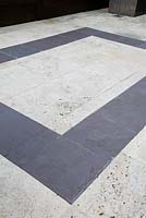 Rectangular design of slate paving set in white stone paving. 