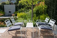 Seating area with white table and chairs under a Corylus colurna, Euphorbia robbiae, Anthriscus sylvestris and Anemone sylvestris, Graduate Gardeners: The Sunken Retreat Garden, RHS Malvern Spring Festival 2016