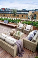 Outside seating area on a London roof terrace with glass top table with a vase of white anemones.  April. 