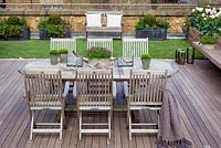 Dining table and chairs with faux lawn on a London roof terrace garden. April. 